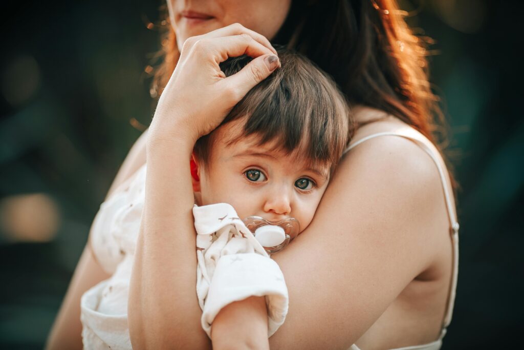 A touching close-up of a mother lovingly holding her baby outdoors.