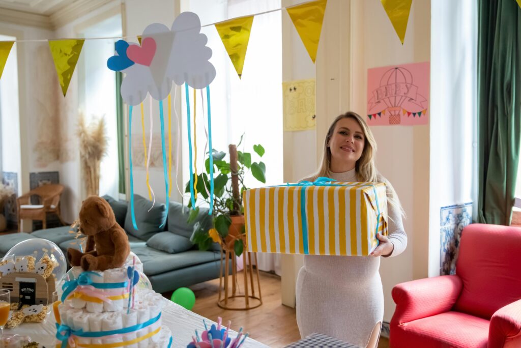 A pregnant woman celebrating at a baby shower with decorations and gifts.